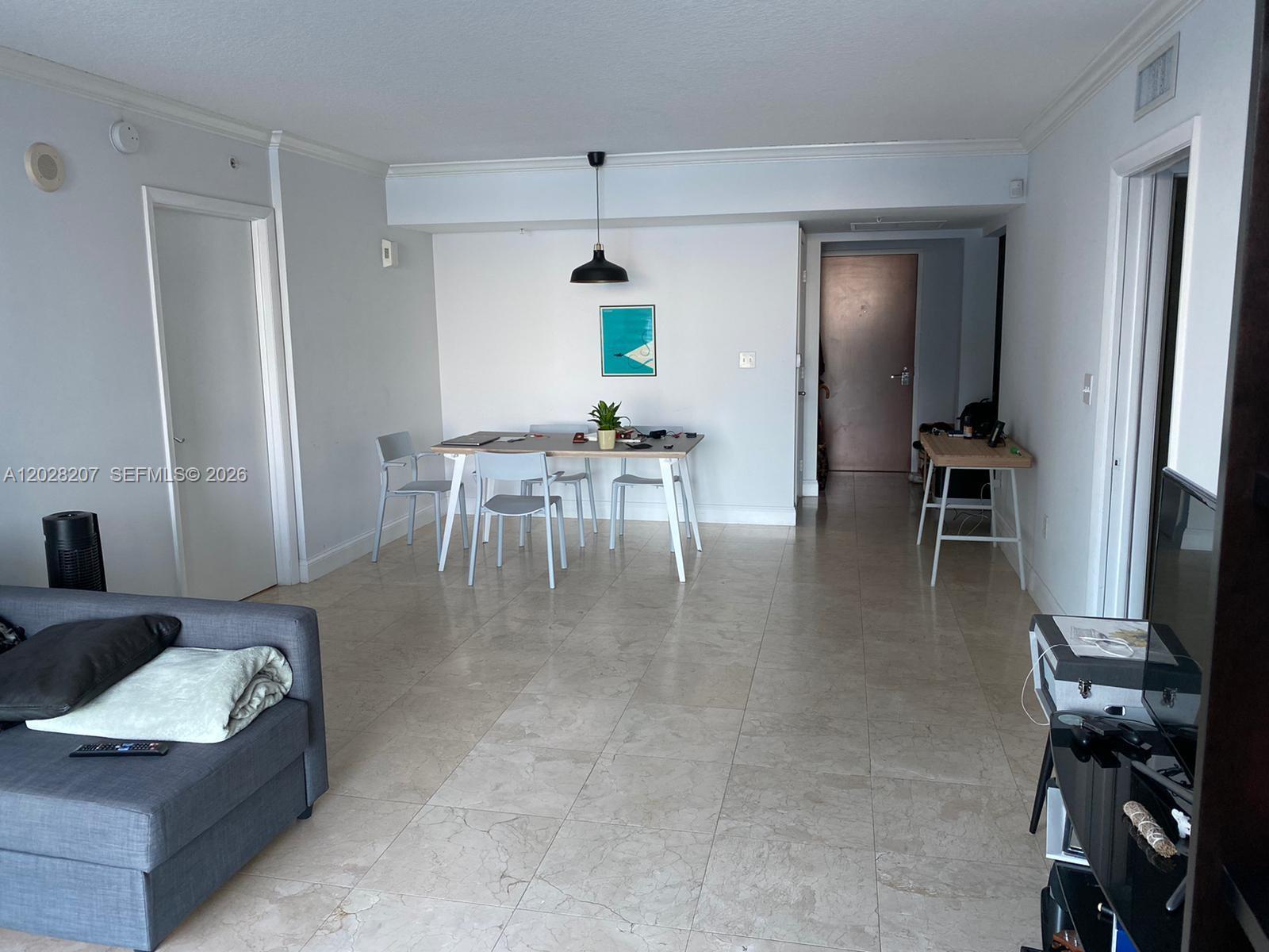A living and dining area features light tile flooring, white walls, and a modern pendant light — 31 SE 5th St # 2308, Miami FL 33131, MIAMI, FL