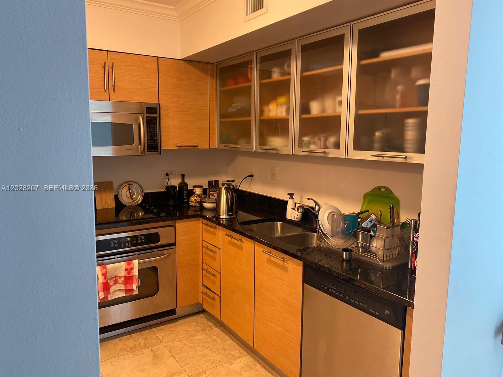 A kitchen features light wood cabinets, stainless steel appliances, and black granite countertops — 31 SE 5th St # 2308, Miami FL 33131, MIAMI, FL