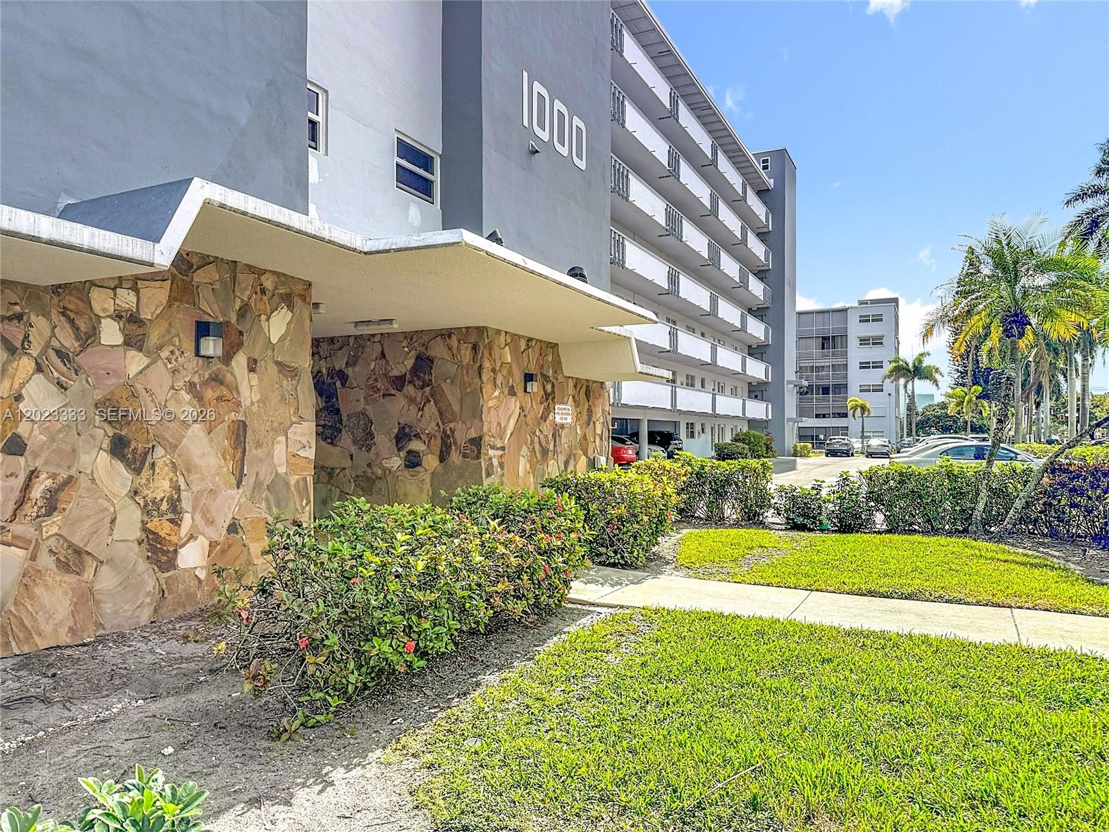 A multi-story apartment building features a stone-clad entrance and a concrete walkway — 1000 NE 14th Ave # 411, Hallandale Beach FL 33009, HALLANDALE BEACH, FL
