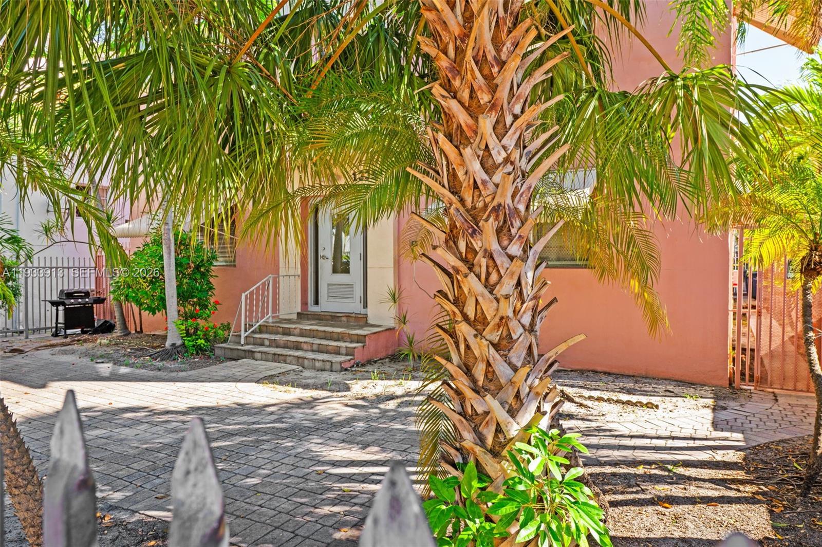A pink house exterior features a palm tree, brick paver driveway, and front entrance steps — 1335 Drexel Ave, Miami Beach FL 33139, MIAMI BEACH, FL