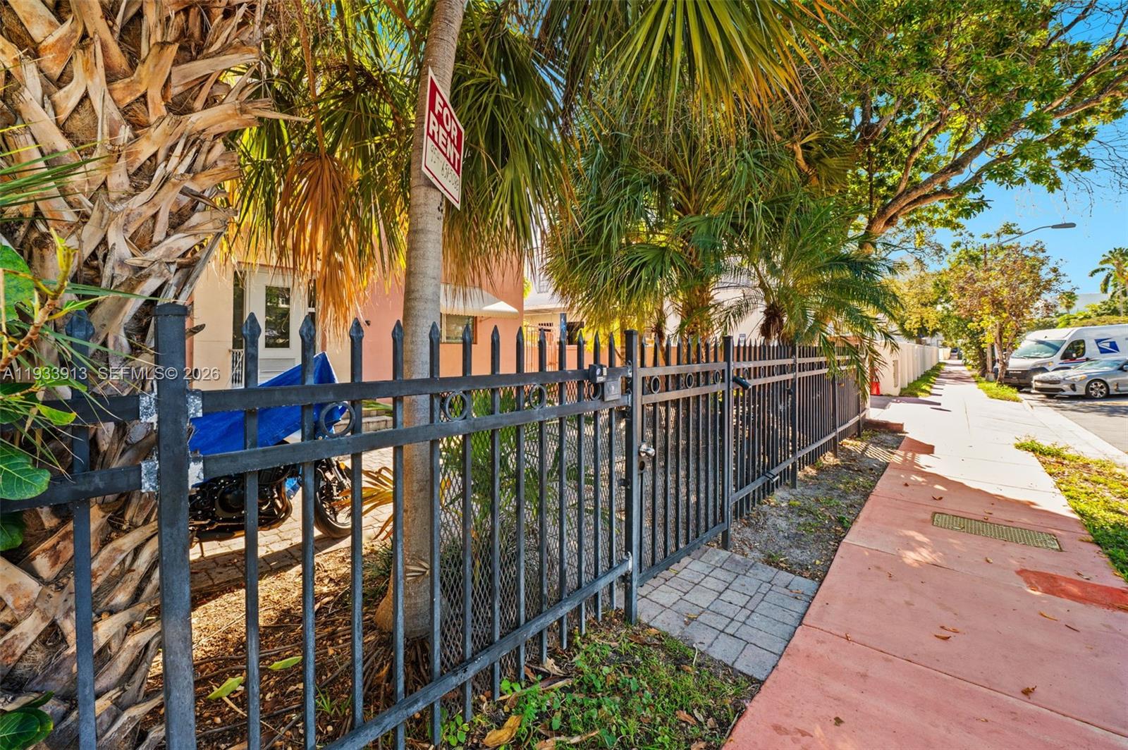 A black metal fence encloses a property with a palm tree and a rental sign — 1335 Drexel Ave, Miami Beach FL 33139, MIAMI BEACH, FL