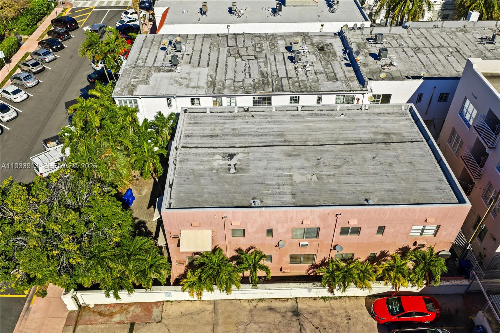 An aerial view shows a pink apartment building with a flat roof and palm trees — 1335 Drexel Ave, Miami Beach FL 33139, MIAMI BEACH, FL