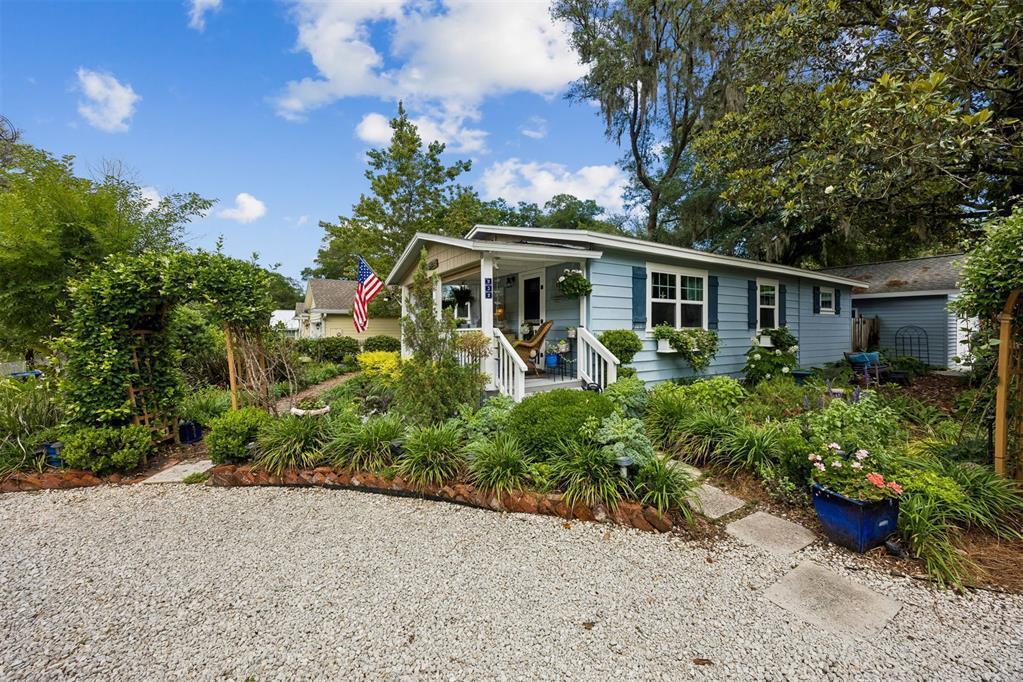 A light blue cottage with a gravel driveway, front porch, and lush garden landscaping — 232 Vernon Street, FL 32034, FL