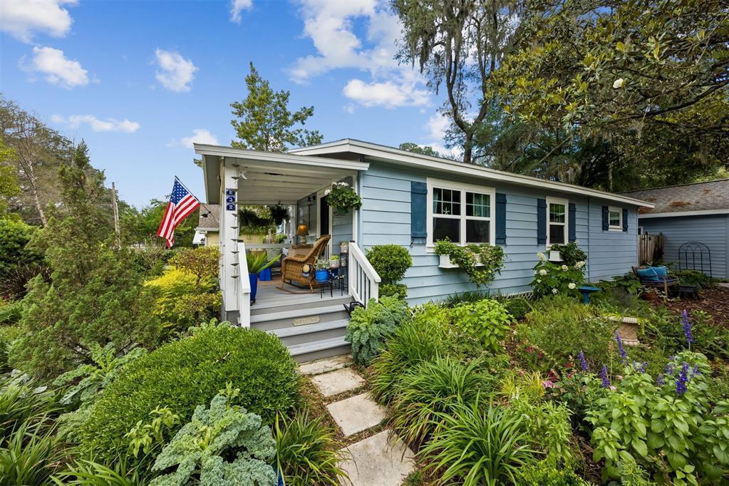 A light blue house with a front porch, American flag, and lush garden landscaping — 232 Vernon Street, FL 32034, FL