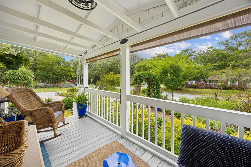 A covered wooden porch features a wicker rocking chair, white railings, and views of greenery — 232 Vernon Street, FL 32034, FL