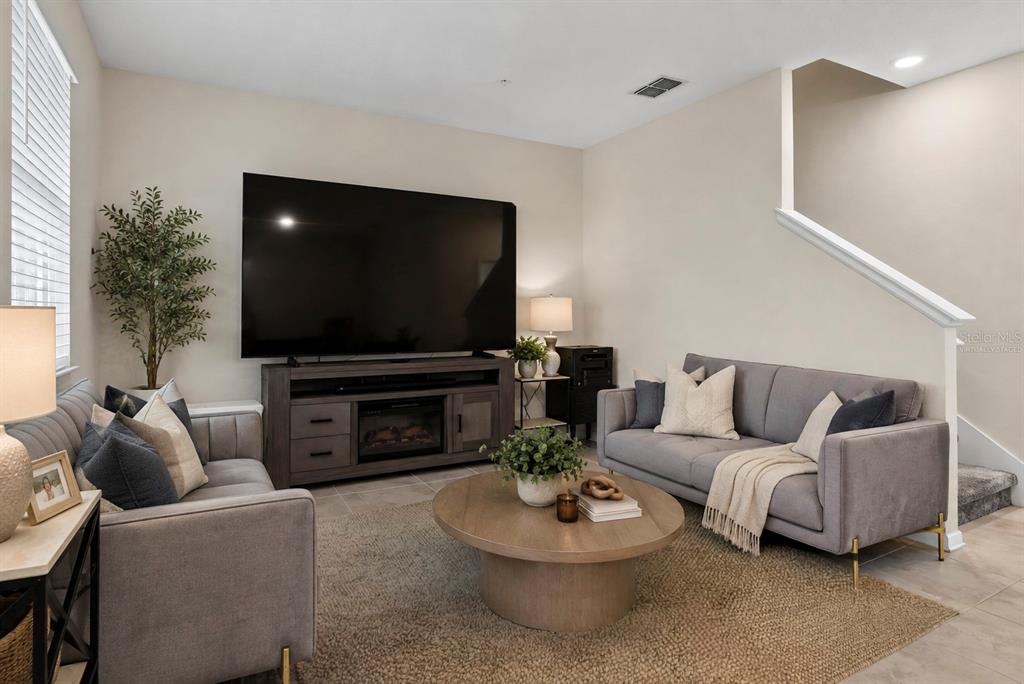 A living room features two gray sofas, a round coffee table, and a large television — 3105 AQUA VIRGO LOOP, ORLANDO, FL