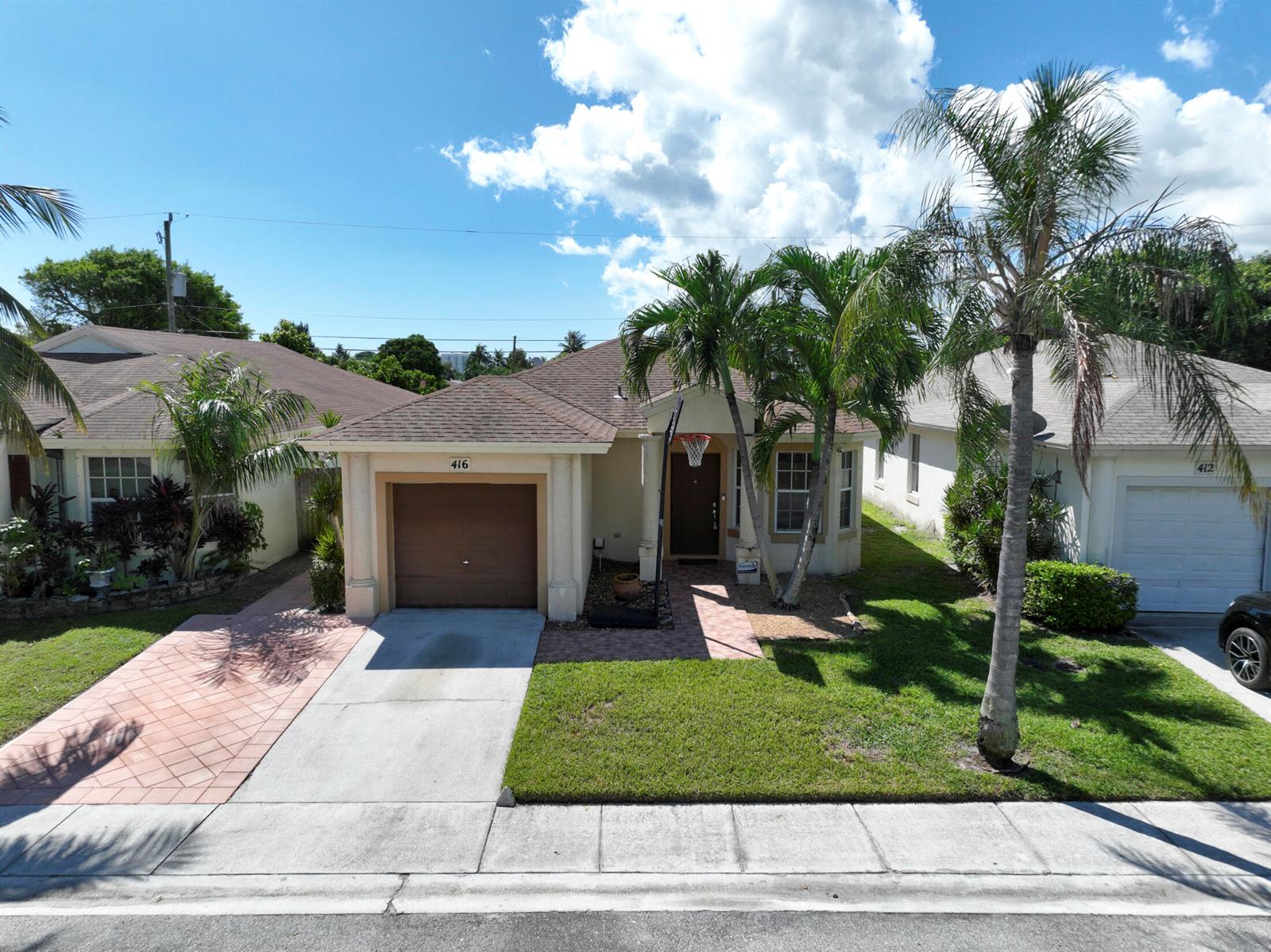 A single-story house with a brown garage, a paved walkway, and palm trees in front — 416 Circle Drive S, Boynton Beach FL 33435, BOYNTON BEACH, FL