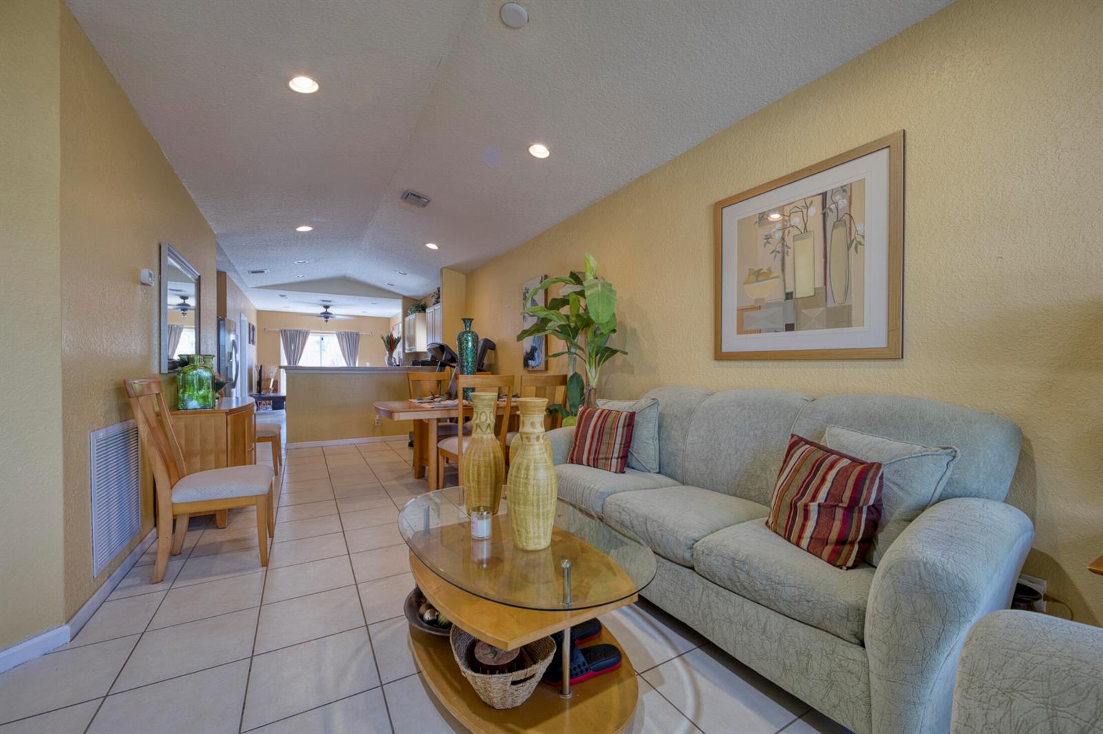 A living room with a light green sofa, glass coffee table, and tile flooring — 416 Circle Drive S, Boynton Beach FL 33435, BOYNTON BEACH, FL