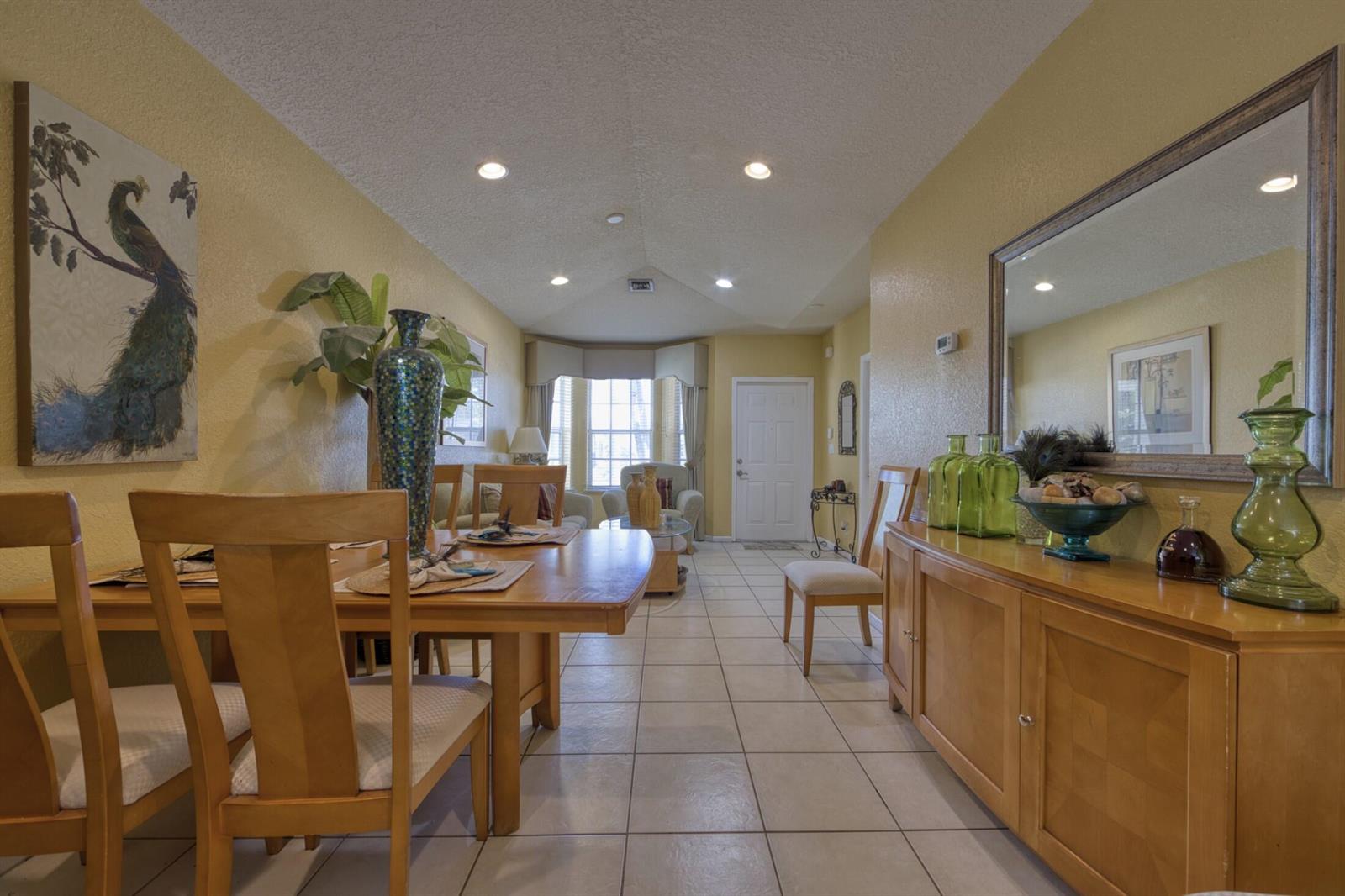 A dining room with a wooden table and sideboard, tile floors, and yellow walls — 416 Circle Drive S, Boynton Beach FL 33435, BOYNTON BEACH, FL