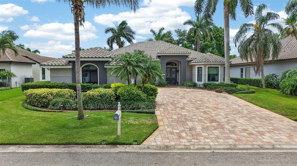 A single-story house with a tiled roof, paver driveway, and palm trees in the front yard — 820 SAND PINE DRIVE NE, ST PETERSBURG, FL