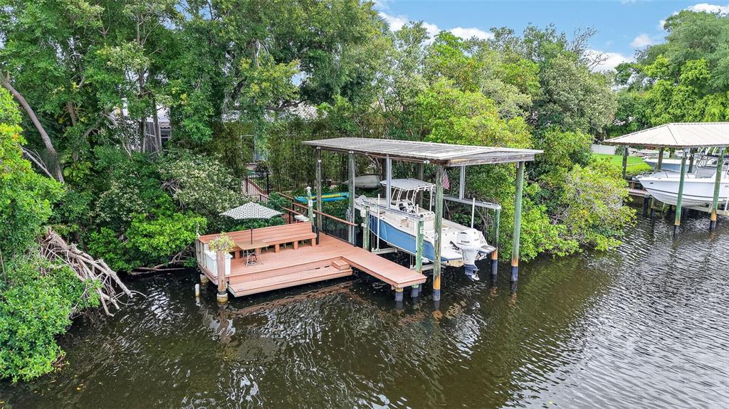 An elevated view shows a wooden dock with a boat lift and a covered slip — 820 SAND PINE DRIVE NE, ST PETERSBURG, FL