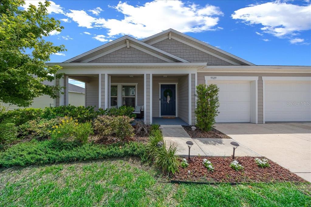 A single-story house with a beige exterior, a front porch, and a two-car garage — 9329 SW 57TH TERRACE, OCALA, FL