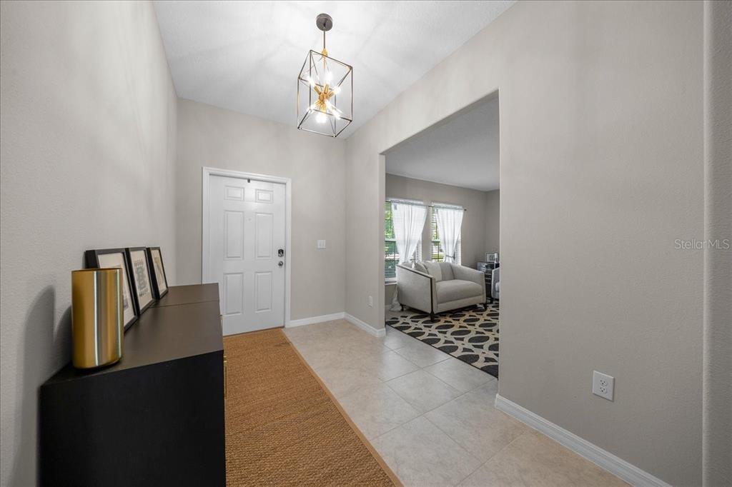 An entryway features a light fixture, a console table, and a view into a living room — 9329 SW 57TH TERRACE, OCALA, FL