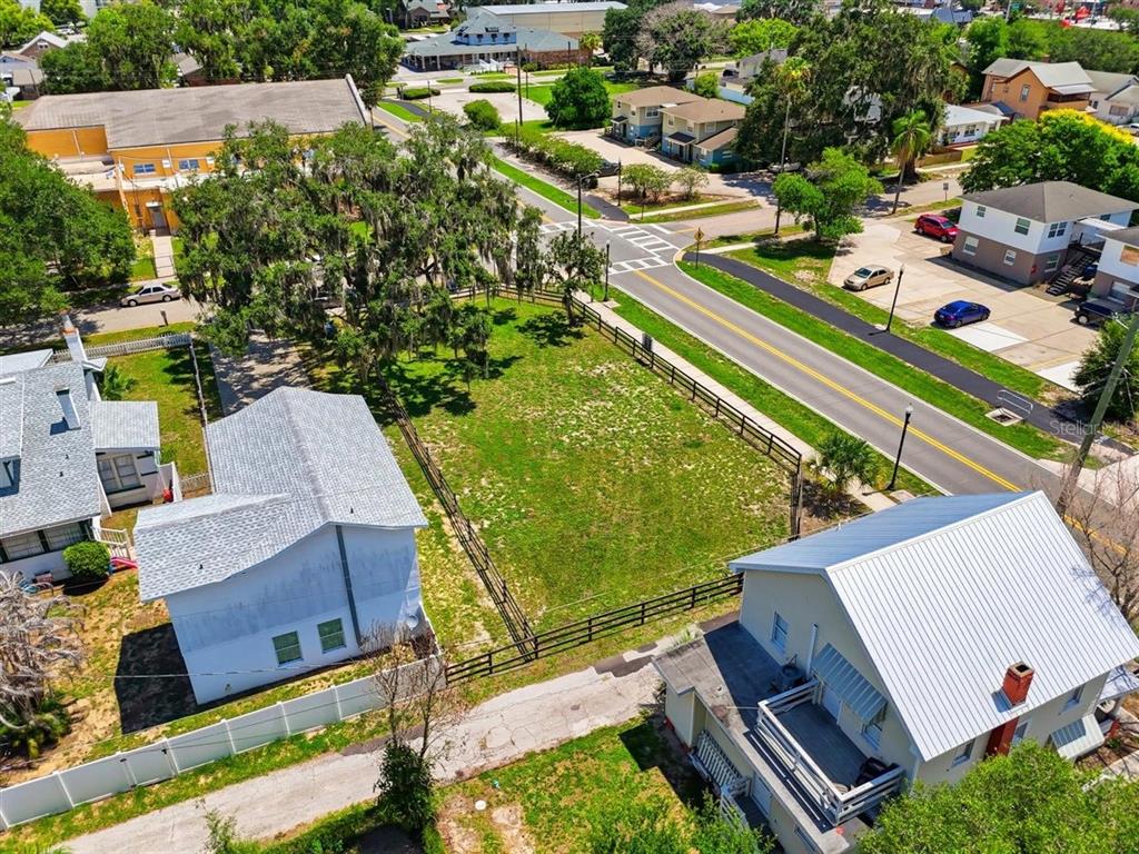 An aerial view shows a vacant grassy lot situated between two houses near a road — 702 AVENUE A, WINTER HAVEN, FL
