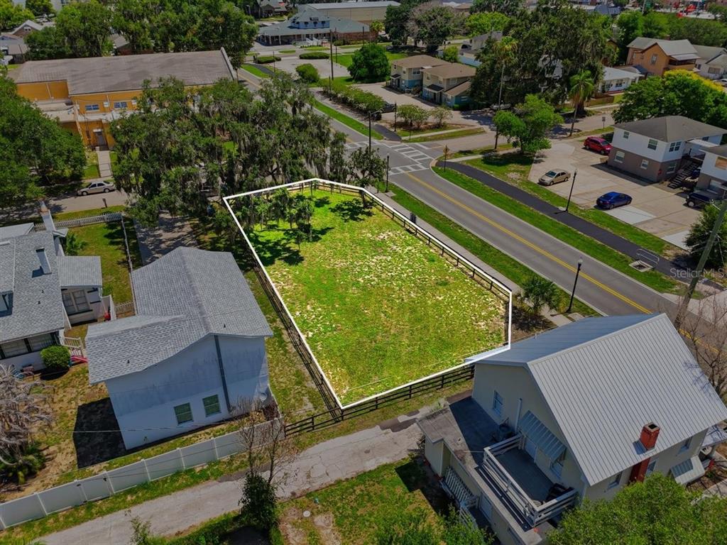 An aerial view shows a fenced, vacant rectangular lot situated between two residential houses — 702 AVENUE A, WINTER HAVEN, FL
