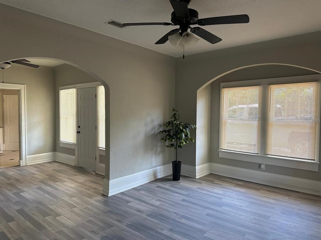 An arched doorway connects a living area with wood-look flooring to a kitchen beyond — 221 N JULIA AVENUE, DELAND, FL