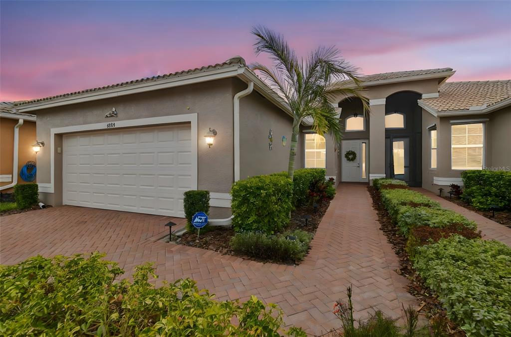 A single-story house with a brick paver driveway, walkway, and a two-car garage at dusk — 4834 MARBLE SPRINGS CIRCLE, WIMAUMA, FL