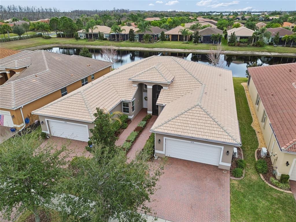 An aerial view shows a single-story house with a tan tile roof and brick driveway — 4834 MARBLE SPRINGS CIRCLE, WIMAUMA, FL