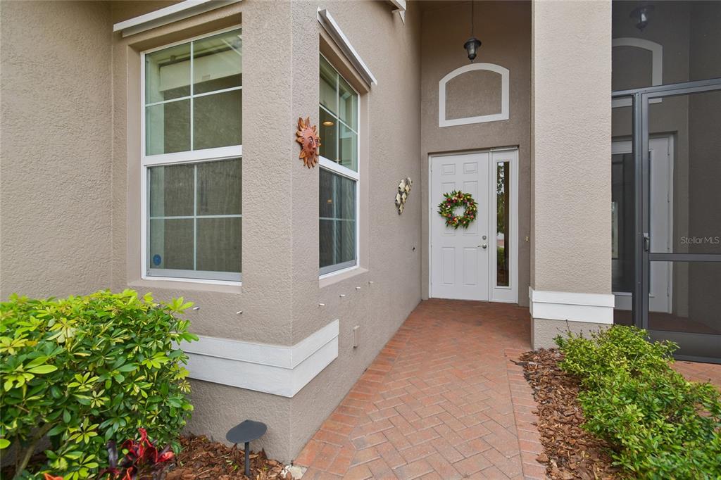 A brick walkway leads to the front entrance of a house with beige stucco walls — 4834 MARBLE SPRINGS CIRCLE, WIMAUMA, FL