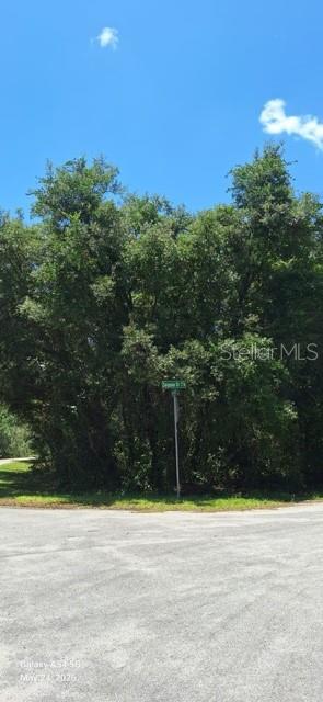 A street sign stands in front of a dense cluster of trees on a sunny day — SEQUOIA DRIVE Lot 5, OCKLAWAHA, FL