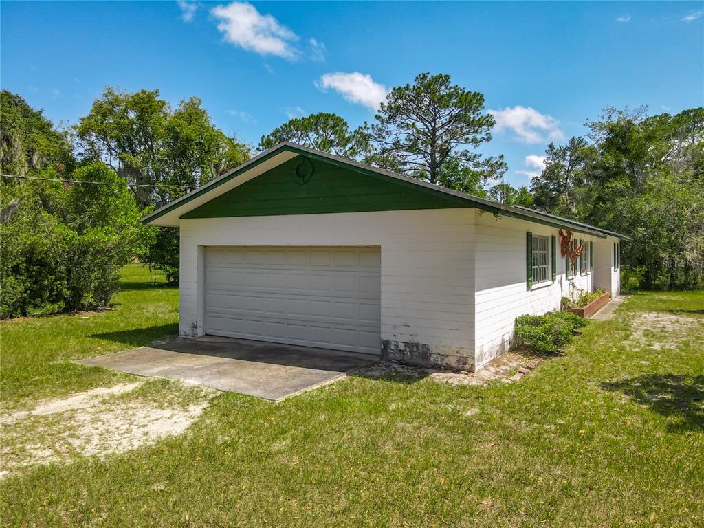 A grassy, open lot features several scattered trees against a backdrop of dense woods — 10 MIRROR LAKE DRIVE, ORMOND BEACH, FL
