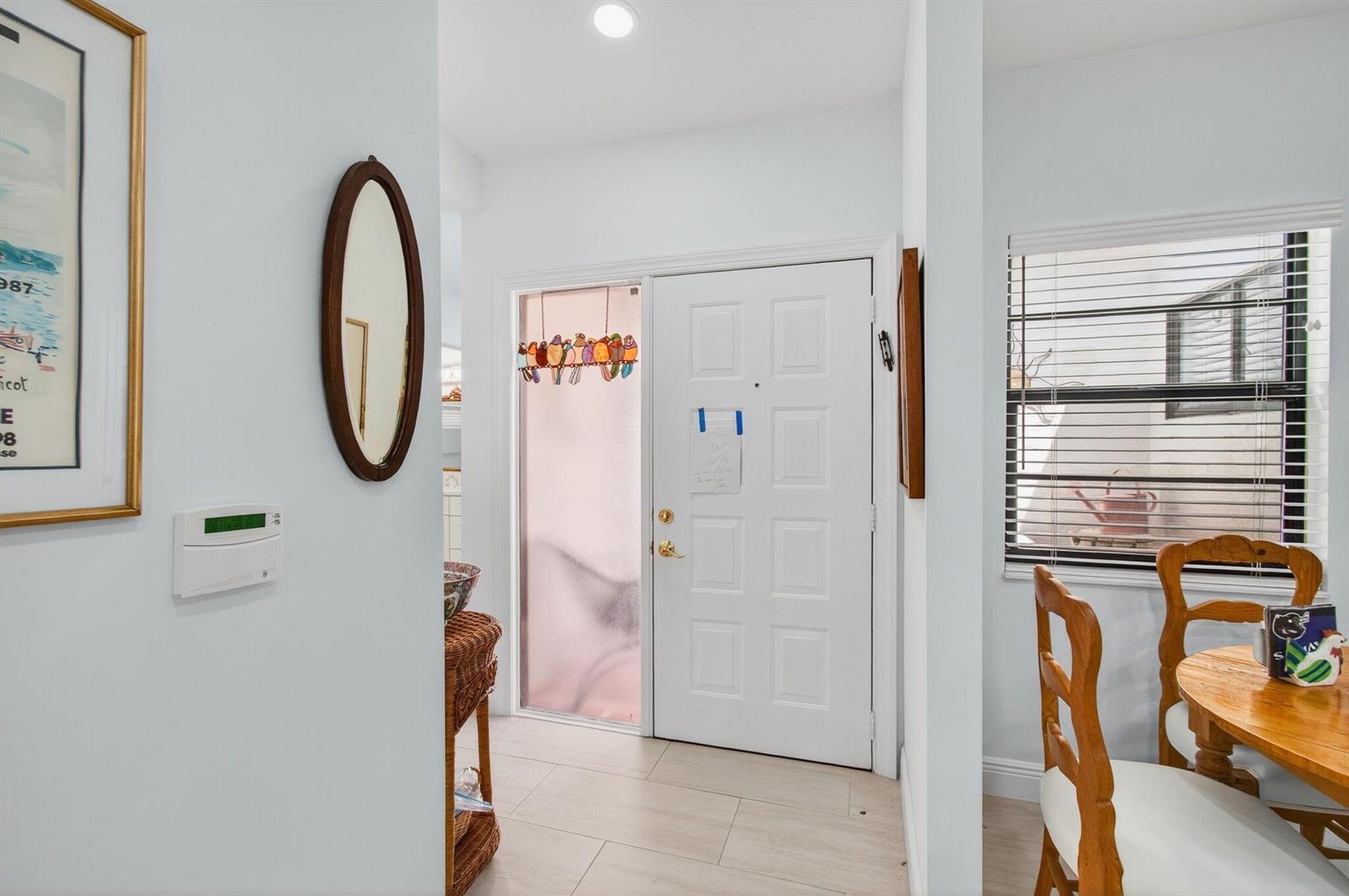 An entryway features a white front door with a stained-glass bird accent and tile flooring — 6248 Kings Gate Circle, Delray Beach FL 33484, DELRAY BEACH, FL