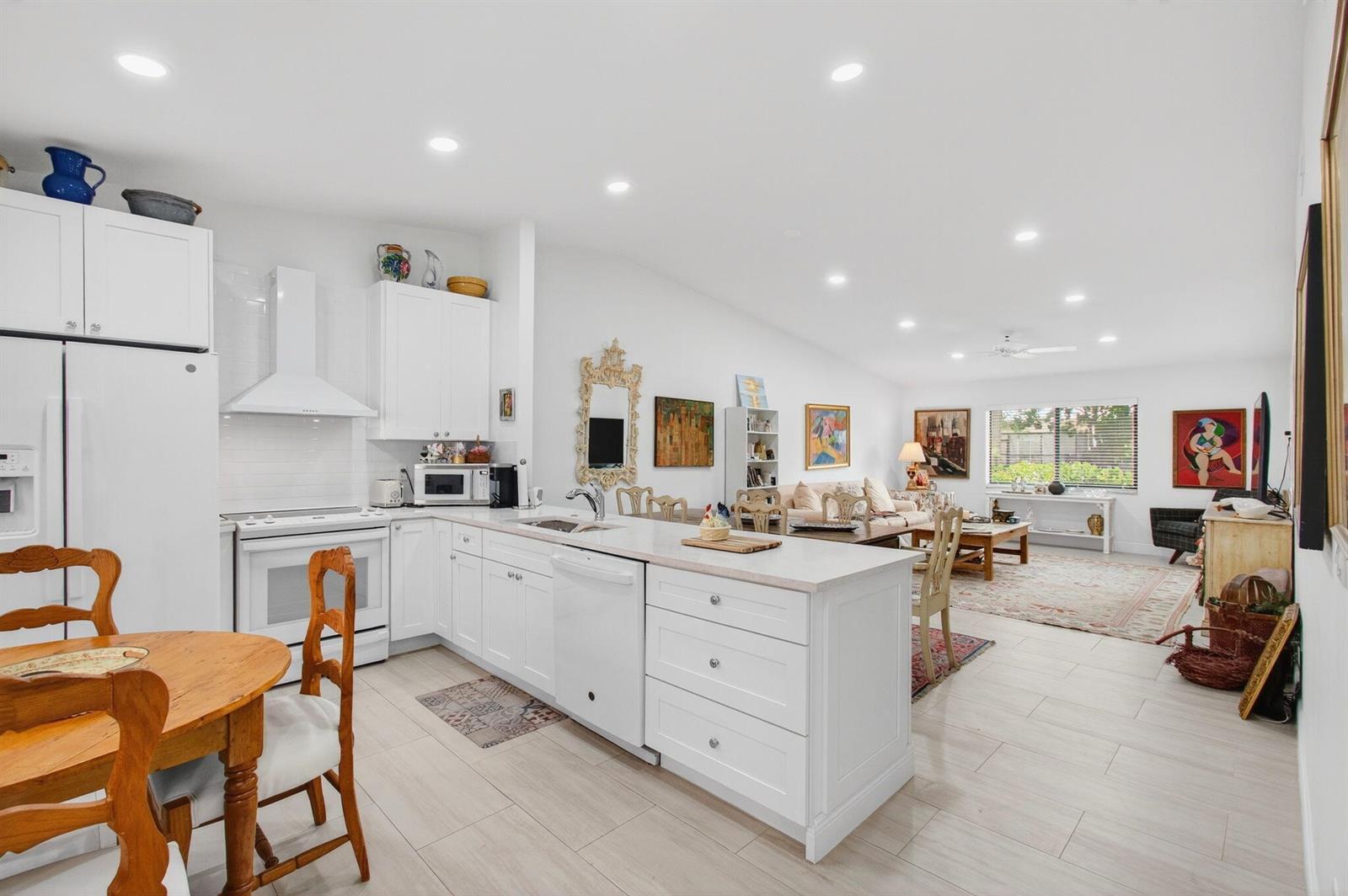 An open-concept kitchen with white cabinetry and an island flows into a bright living area — 6248 Kings Gate Circle, Delray Beach FL 33484, DELRAY BEACH, FL