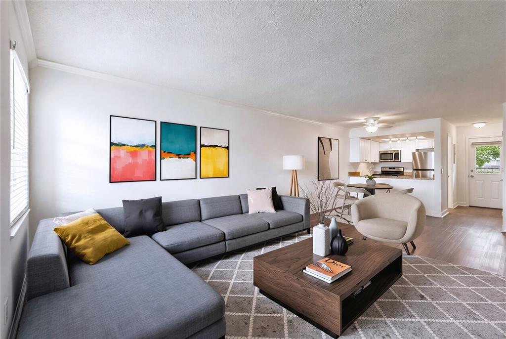 An empty living room features white walls, wood-look flooring, a front door, and a window — 4813 MCELROY UNIT D108, TAMPA, FL