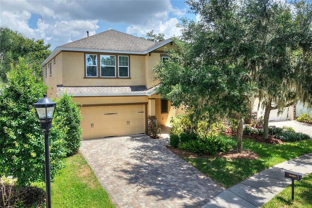 A two-story house with a tan stucco exterior, a paved driveway, and a two-car garage — 16302 BAYBERRY VIEW DRIVE, LITHIA, FL
