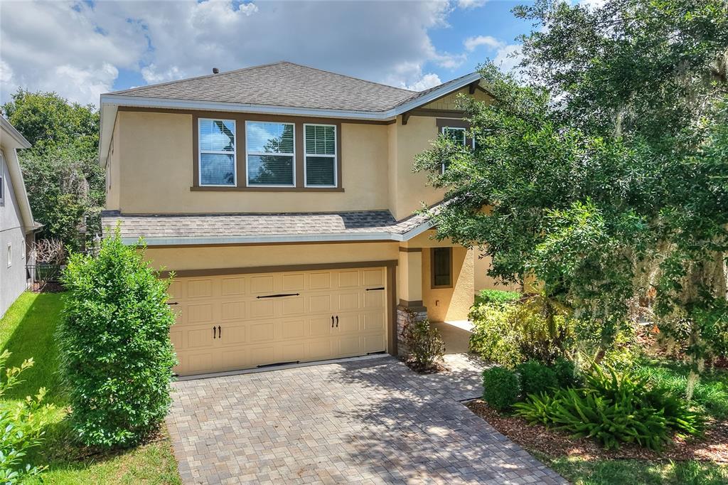 A two-story house with a tan stucco exterior, a two-car garage, and a paved driveway — 16302 BAYBERRY VIEW DRIVE, LITHIA, FL