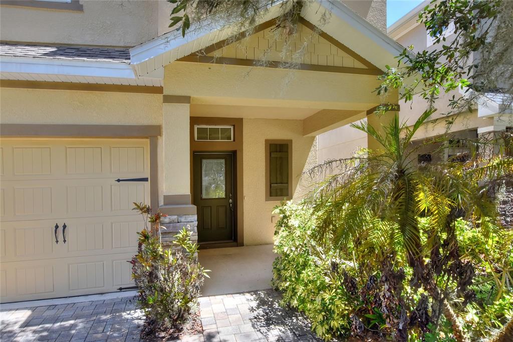 The exterior of a house features a beige garage, a covered entryway, and a front door — 16302 BAYBERRY VIEW DRIVE, LITHIA, FL