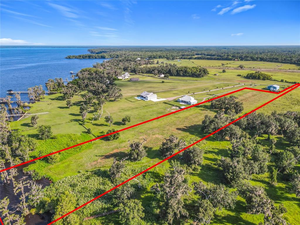 An aerial view shows a large, grassy plot of land outlined in red near a lake — 14453 ANDALUSIA TRAIL, BUNNELL, FL