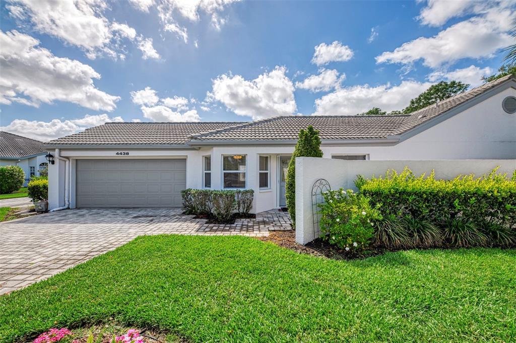 A single-story house with a gray tile roof, a two-car garage, and a front courtyard — 4438 LONG COMMON LANE UNIT 52, SARASOTA, FL