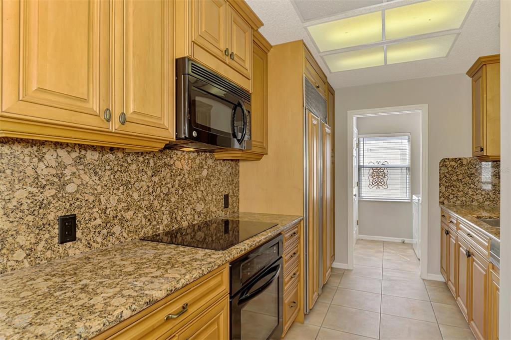 A kitchen features light wood cabinets, granite countertops, a built-in oven, and a tile floor — 4438 LONG COMMON LANE UNIT 52, SARASOTA, FL