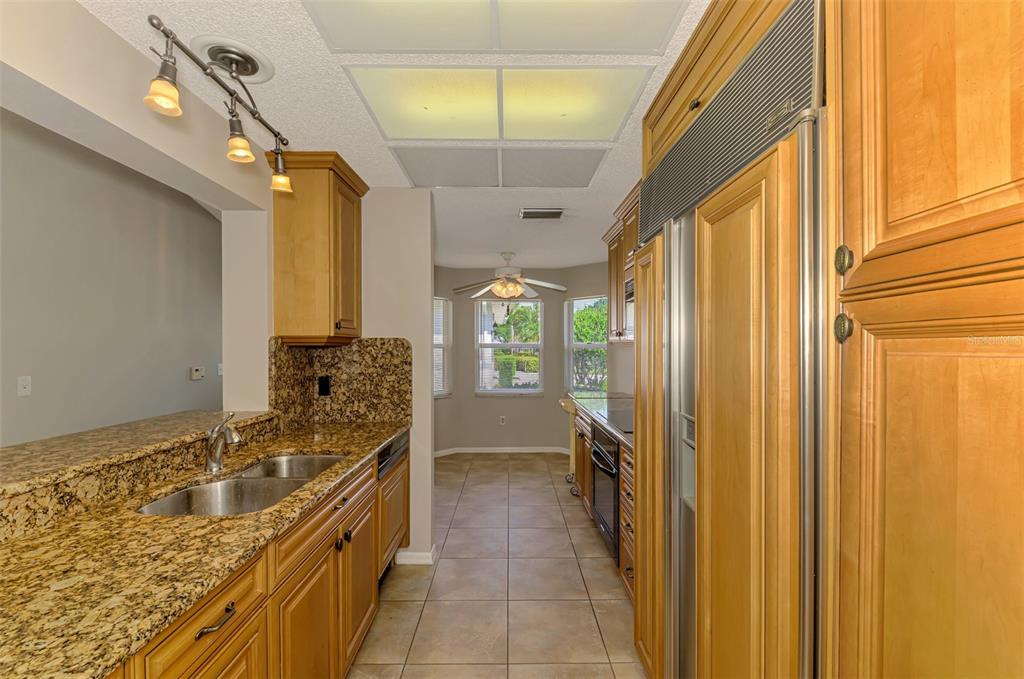 A kitchen with light wood cabinets, granite countertops, tile flooring, and a stainless steel refrigerator — 4438 LONG COMMON LANE UNIT 52, SARASOTA, FL