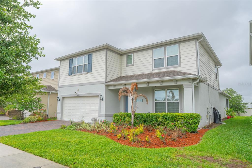 A two-story house with a beige exterior, a two-car garage, and a landscaped front yard — 4120 RAINFALL PLACE, SANFORD, FL