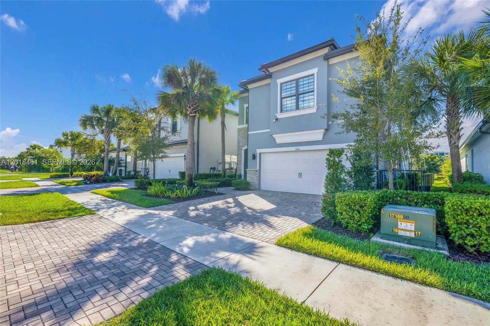 A two-story blue house with a paved driveway and palm trees under a sunny sky — 2454 Primrose Pl, Oakland Park FL 33309, OAKLAND PARK, FL