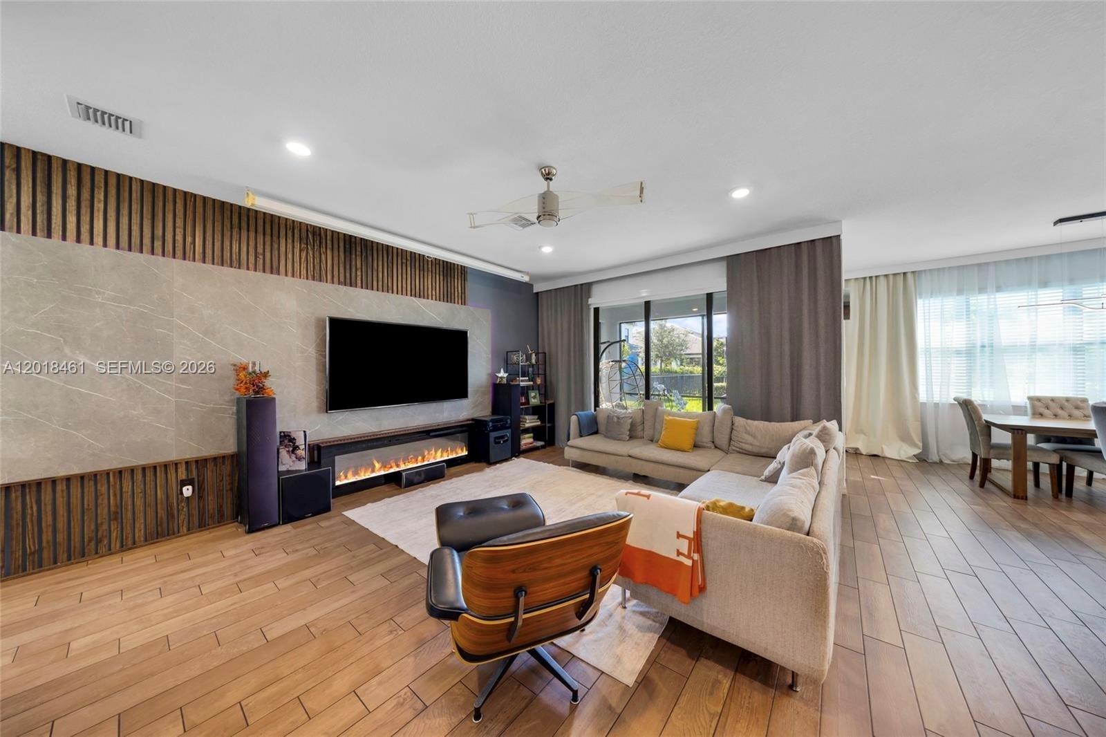 A modern living room features a stone-accented media wall, fireplace, and wood-look tile flooring — 2454 Primrose Pl, Oakland Park FL 33309, OAKLAND PARK, FL