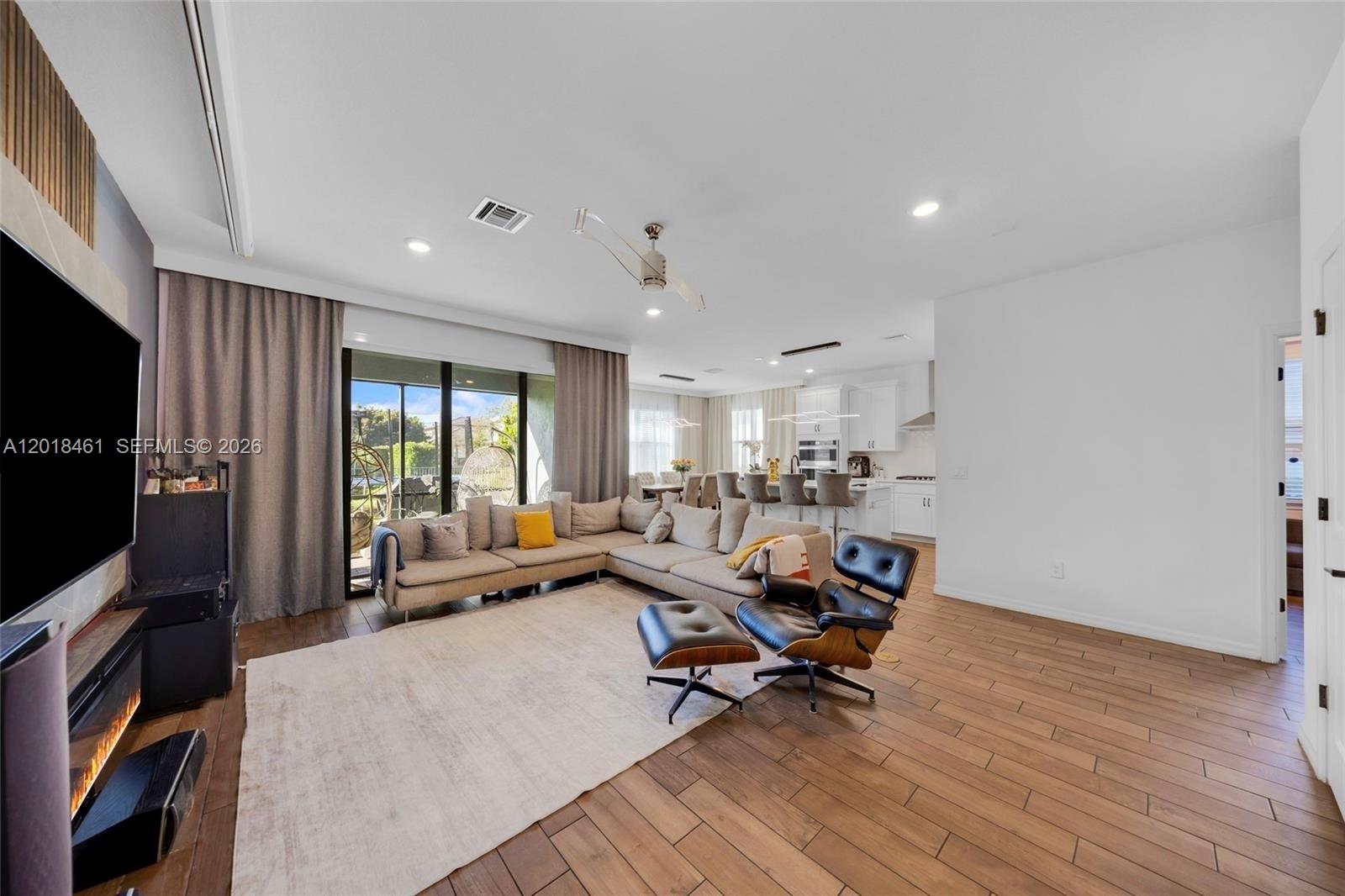 A living room with a sectional sofa, lounge chair, and open kitchen in the background — 2454 Primrose Pl, Oakland Park FL 33309, OAKLAND PARK, FL