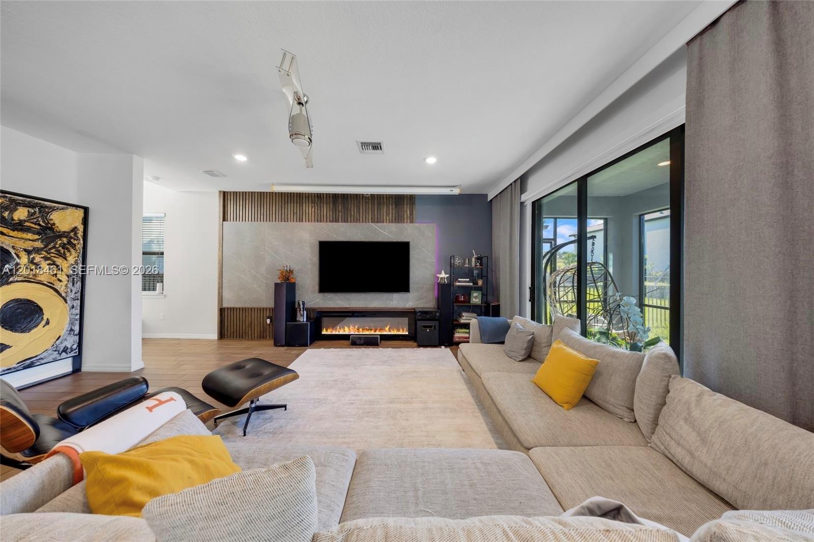 A living room features a large sectional sofa, a fireplace, and a wall-mounted television — 2454 Primrose Pl, Oakland Park FL 33309, OAKLAND PARK, FL
