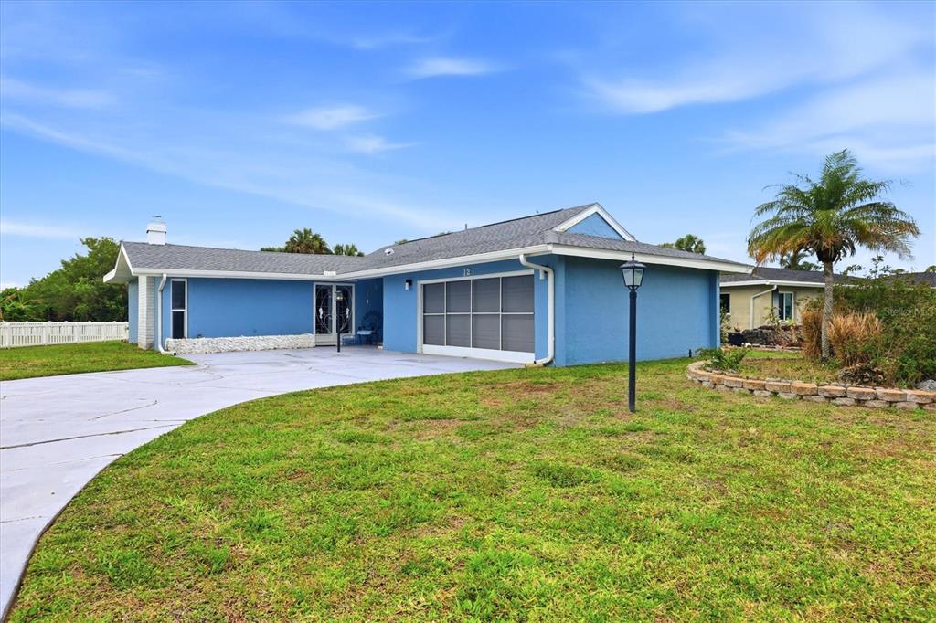 A blue single-story house features a gray shingled roof, a screened garage, and a driveway — 12 GOLFVIEW COURT, ROTONDA WEST, FL