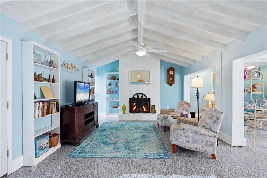 A living room features a white vaulted ceiling, a brick fireplace, and light blue walls — 12 GOLFVIEW COURT, ROTONDA WEST, FL