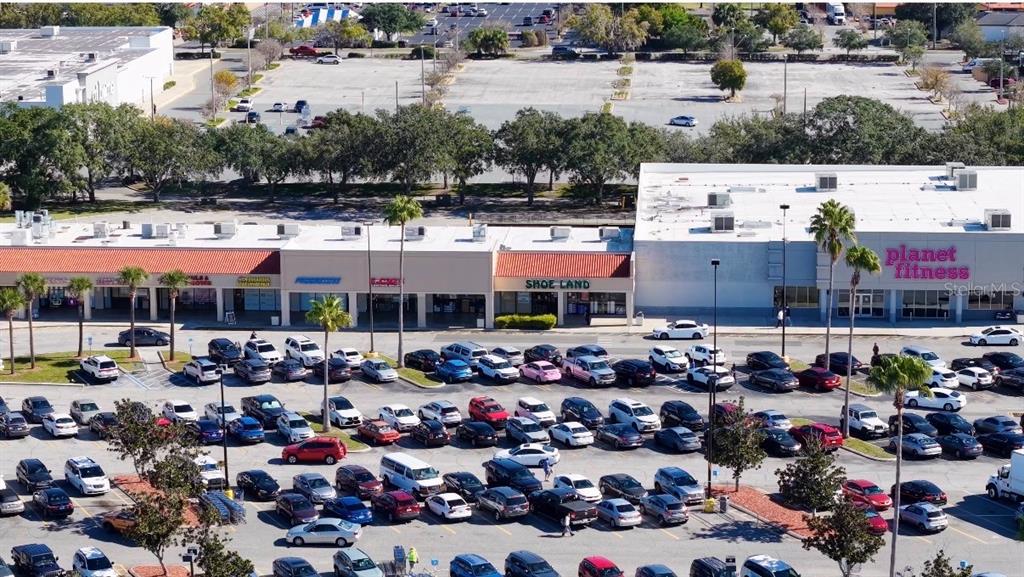 An aerial view shows a strip mall with a Planet Fitness and a large parking lot — 3153 W VINE STREET, KISSIMMEE, FL