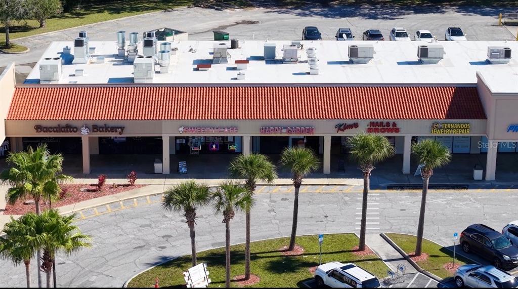 An aerial view shows a commercial strip mall with several storefronts and a parking lot — 3153 W VINE STREET, KISSIMMEE, FL