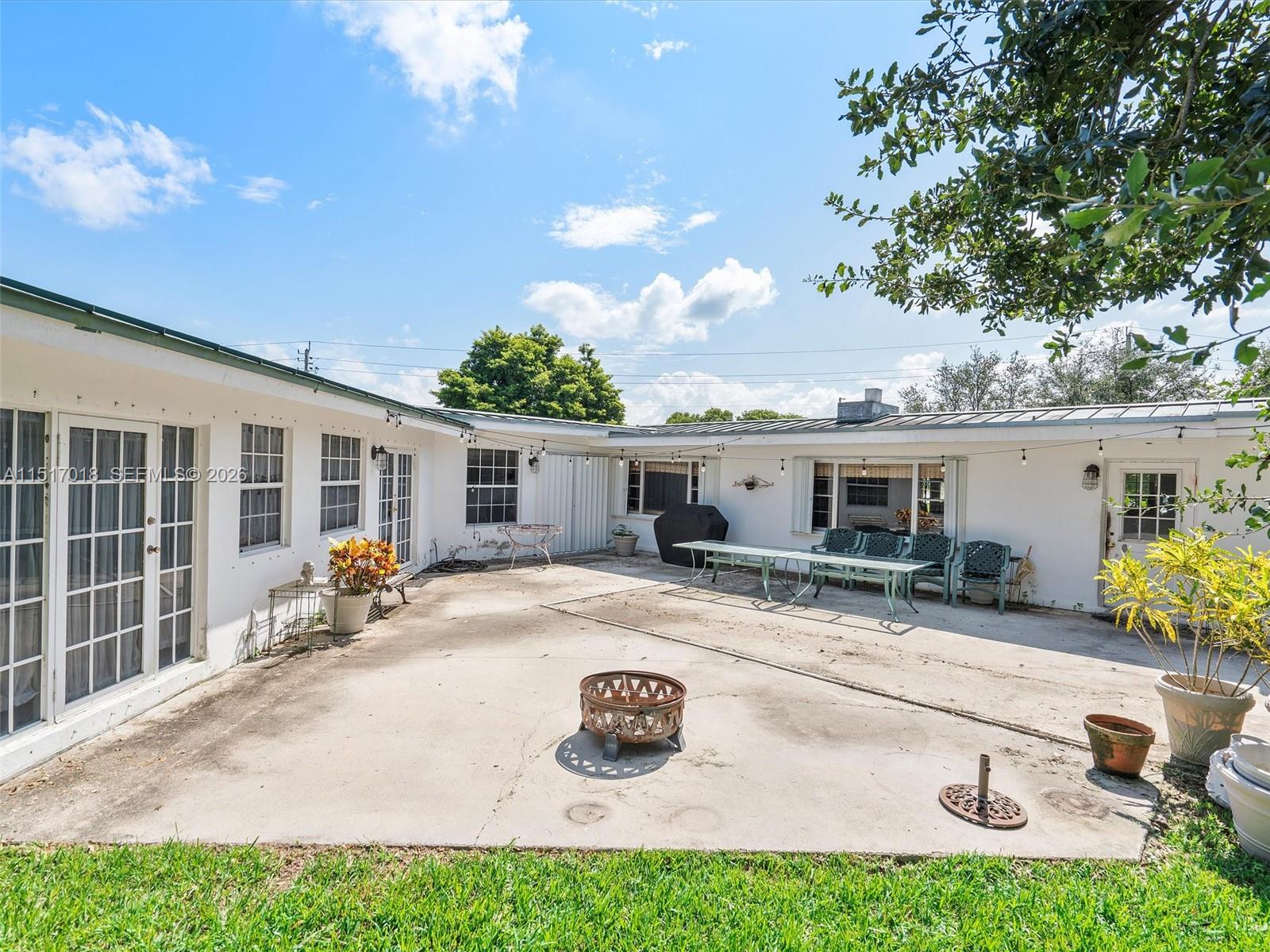 A concrete patio area features a fire pit, outdoor dining furniture, and white exterior walls — 5901 SW 160th Ave, Southwest Ranches FL 33331, SOUTHWEST RANCHES, FL