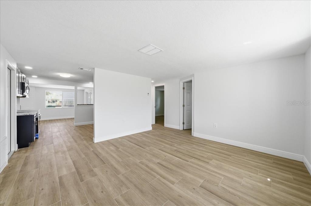 An open-concept living area with light wood-look tile flooring and white walls — 13902 BARNARD AVENUE, HUDSON, FL