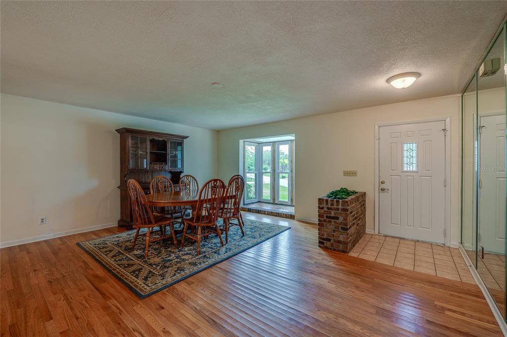 A dining room with hardwood floors, a wooden hutch, and a brick entryway partition — 7 WATERFRONT COURT, ORMOND BEACH, FL