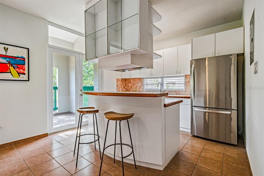 A kitchen features a breakfast bar with two stools, white cabinetry, and stainless steel appliances — 693 NCV UNIT 324, VEGA ALTA, PR
