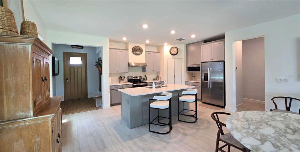 A kitchen features a central island, stainless steel appliances, and light-colored cabinetry — 10583 TUPPER CAY DRIVE, SAN ANTONIO, FL