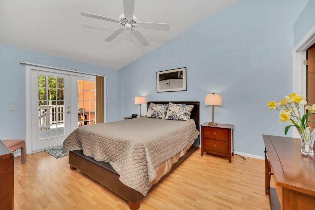 A bedroom with light blue walls, wood flooring, a bed, and a glass door — 3139 BRITANNIA BOULEVARD UNIT C, KISSIMMEE, FL